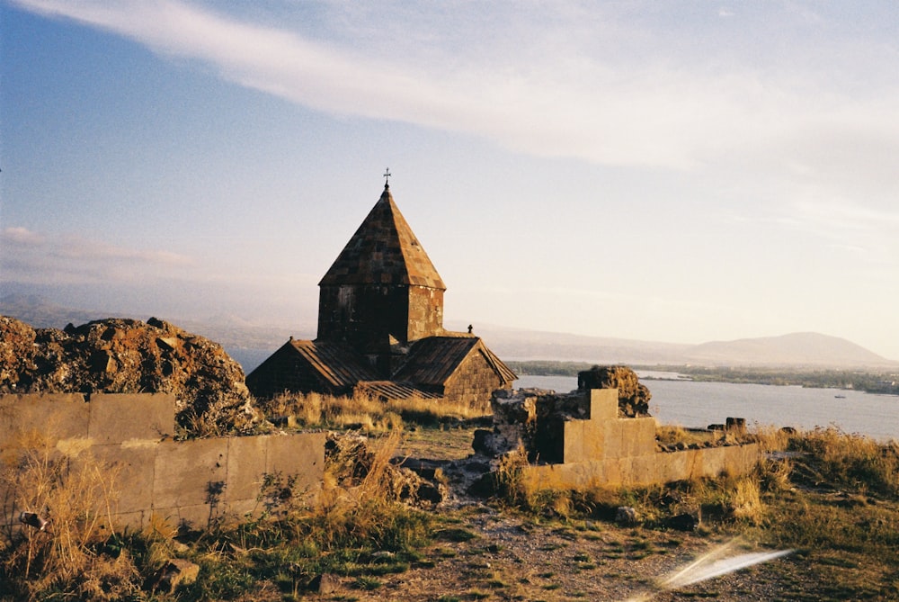 an old church sitting on top of a hill next to a body of water