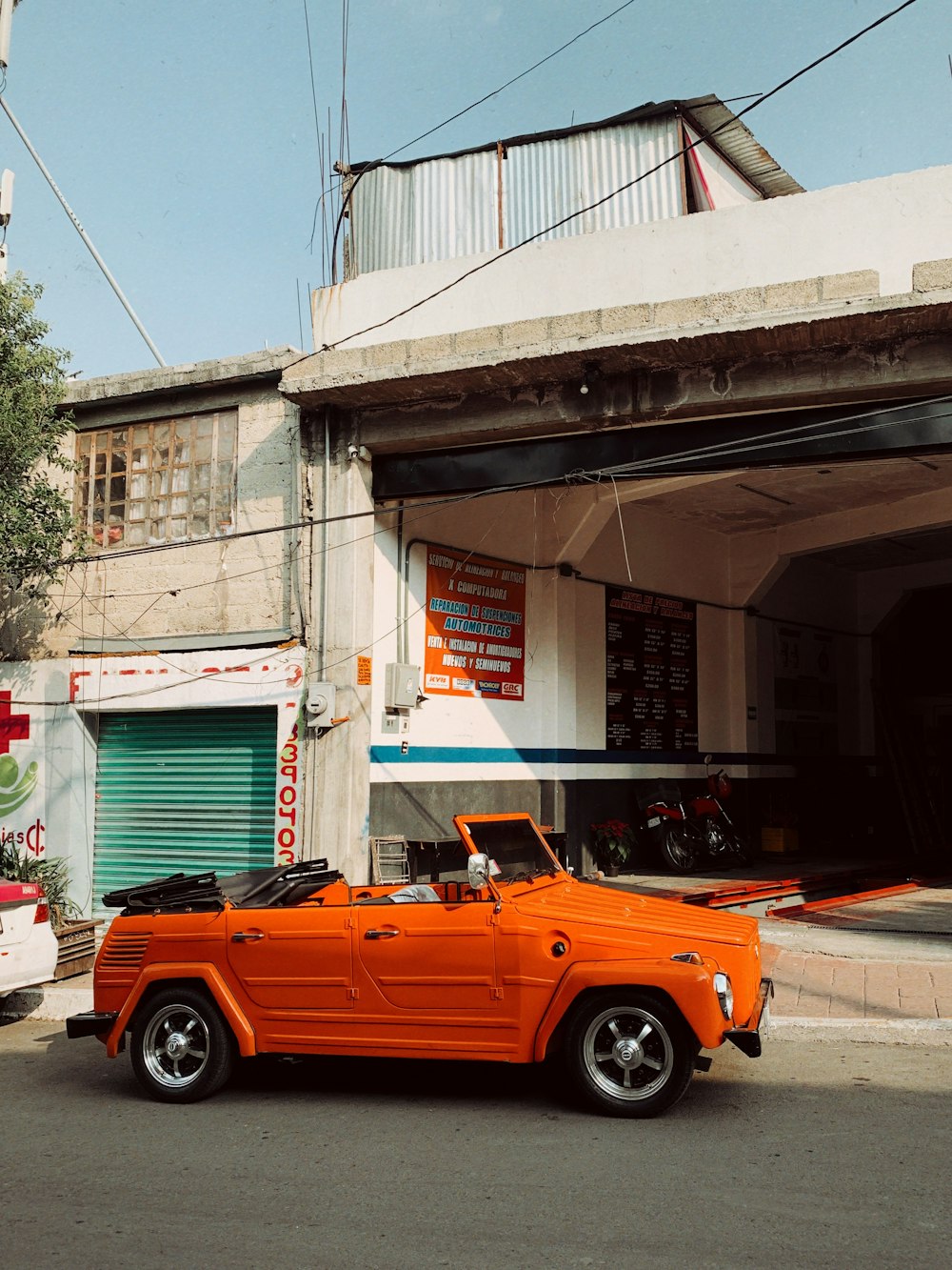 an orange convertible car parked in front of a garage