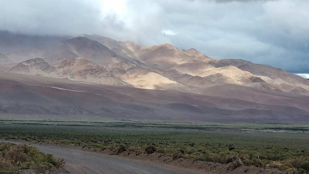 a dirt road in front of a mountain range