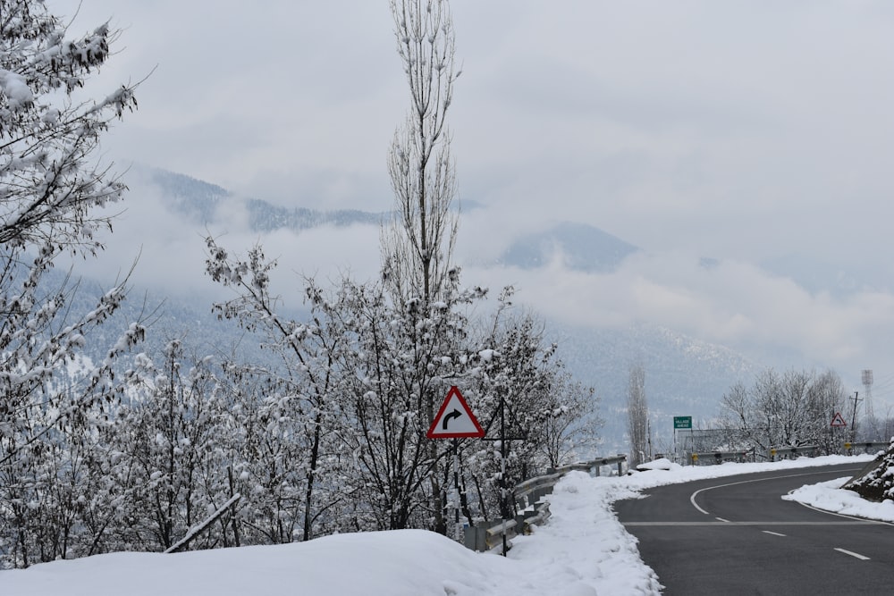 a road with snow on the ground and a sign on the side of the road