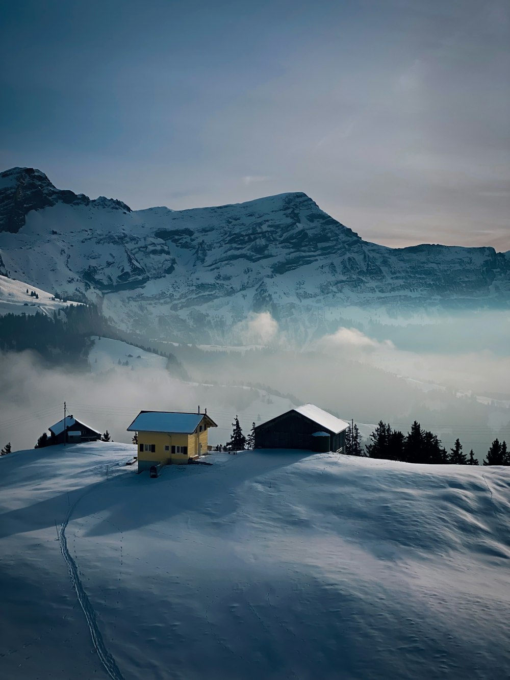 a house on a snowy hill with a mountain in the background