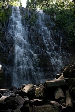 a very tall waterfall in the middle of a forest