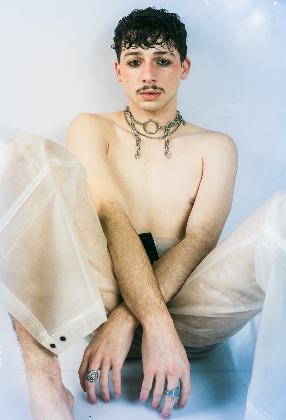 a shirtless man sitting on the ground with his hands on his knees