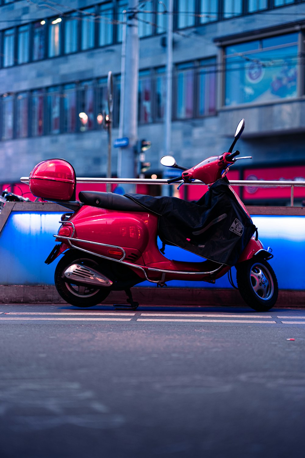 a red scooter parked on the side of the road