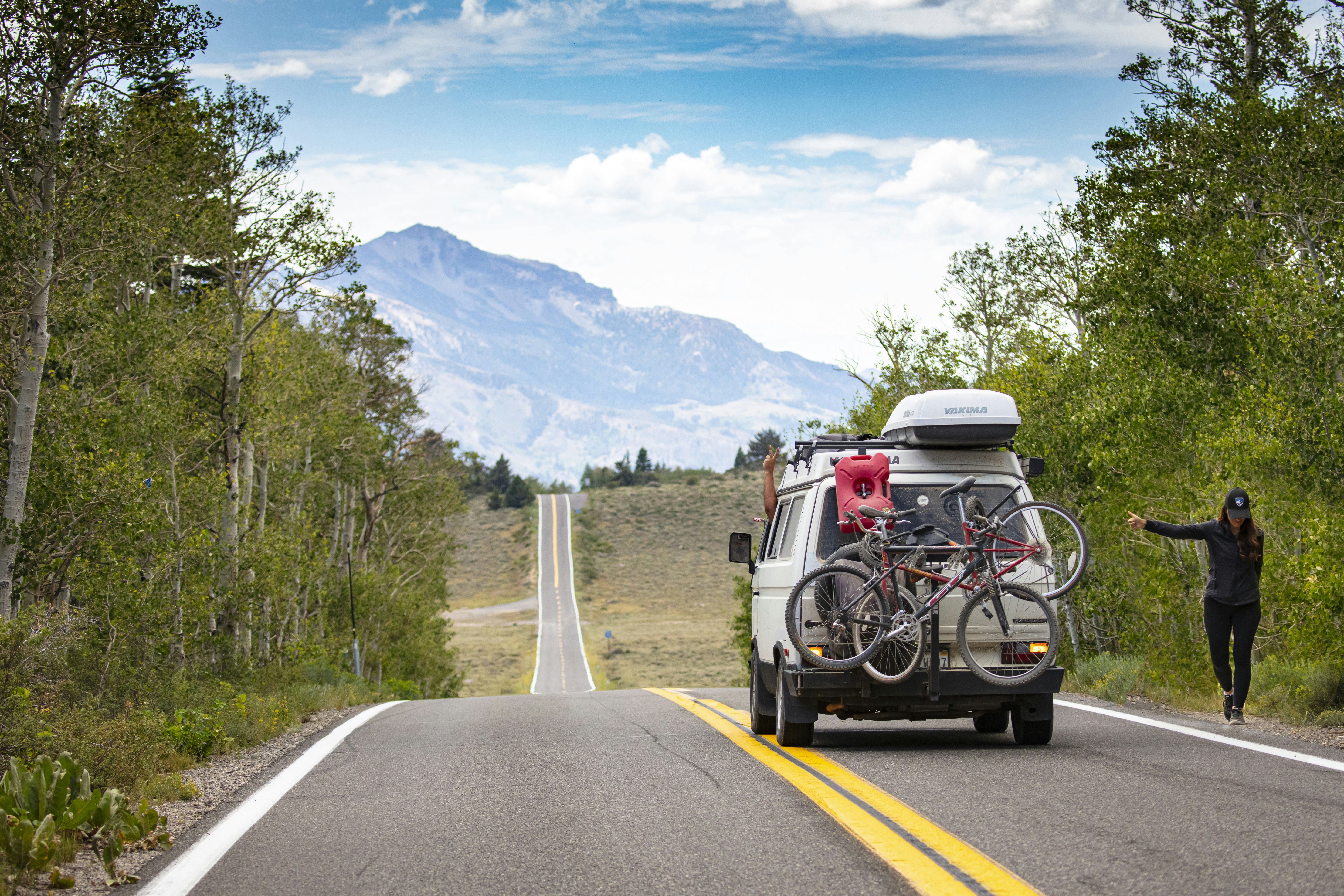 a van with bicycles on the back of it driving down a road