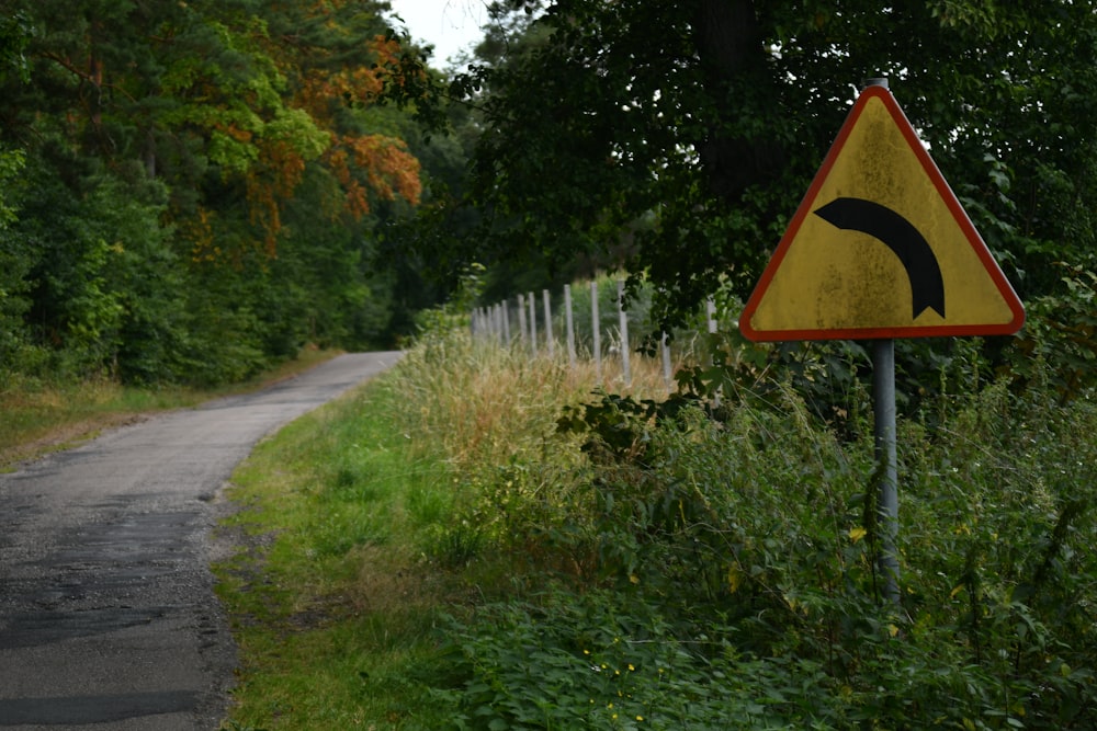 a yellow and black sign sitting on the side of a road