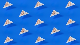 A pattern of small triangular packages, each with a coin featuring a pound symbol, is arranged uniformly across a bright blue background. The design is minimalistic and modern, featuring clean lines and a stark contrast between the blue and the white of the packages.