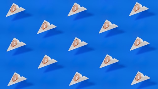 A pattern of small triangular packages, each with a coin featuring a pound symbol, is arranged uniformly across a bright blue background. The design is minimalistic and modern, featuring clean lines and a stark contrast between the blue and the white of the packages.