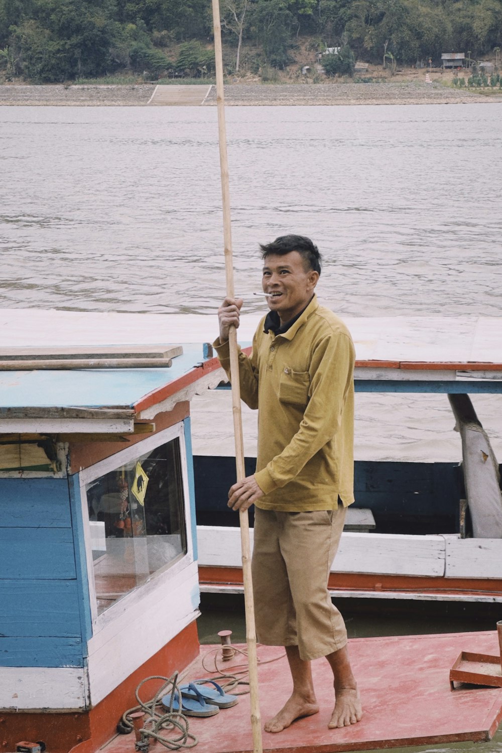 a man standing on a boat holding a pole