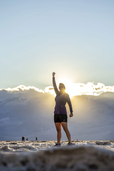 a woman standing on top of a snow covered slope feeling victory with life