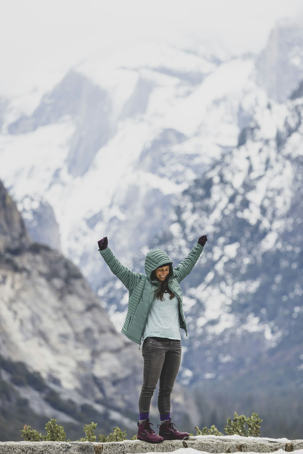 uma mulher em pé no topo de uma montanha coberta de neve