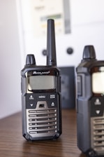 two walkie talkies sitting on top of a wooden table