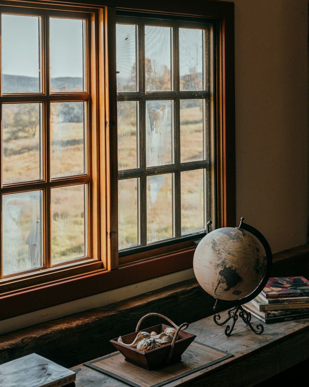 a globe sitting on top of a wooden table next to a window