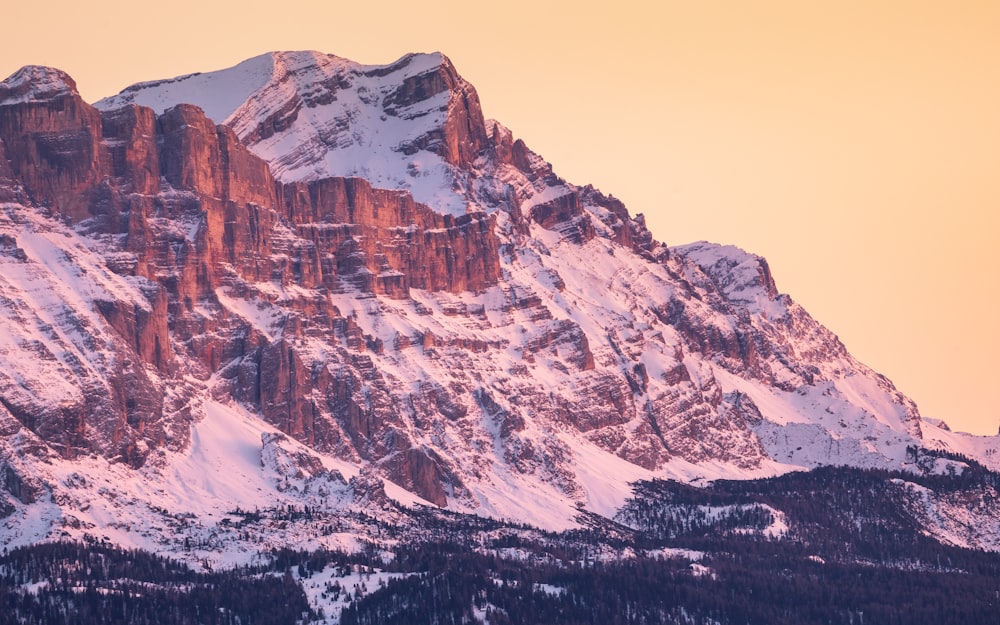 a snow covered mountain with a pink sky in the background