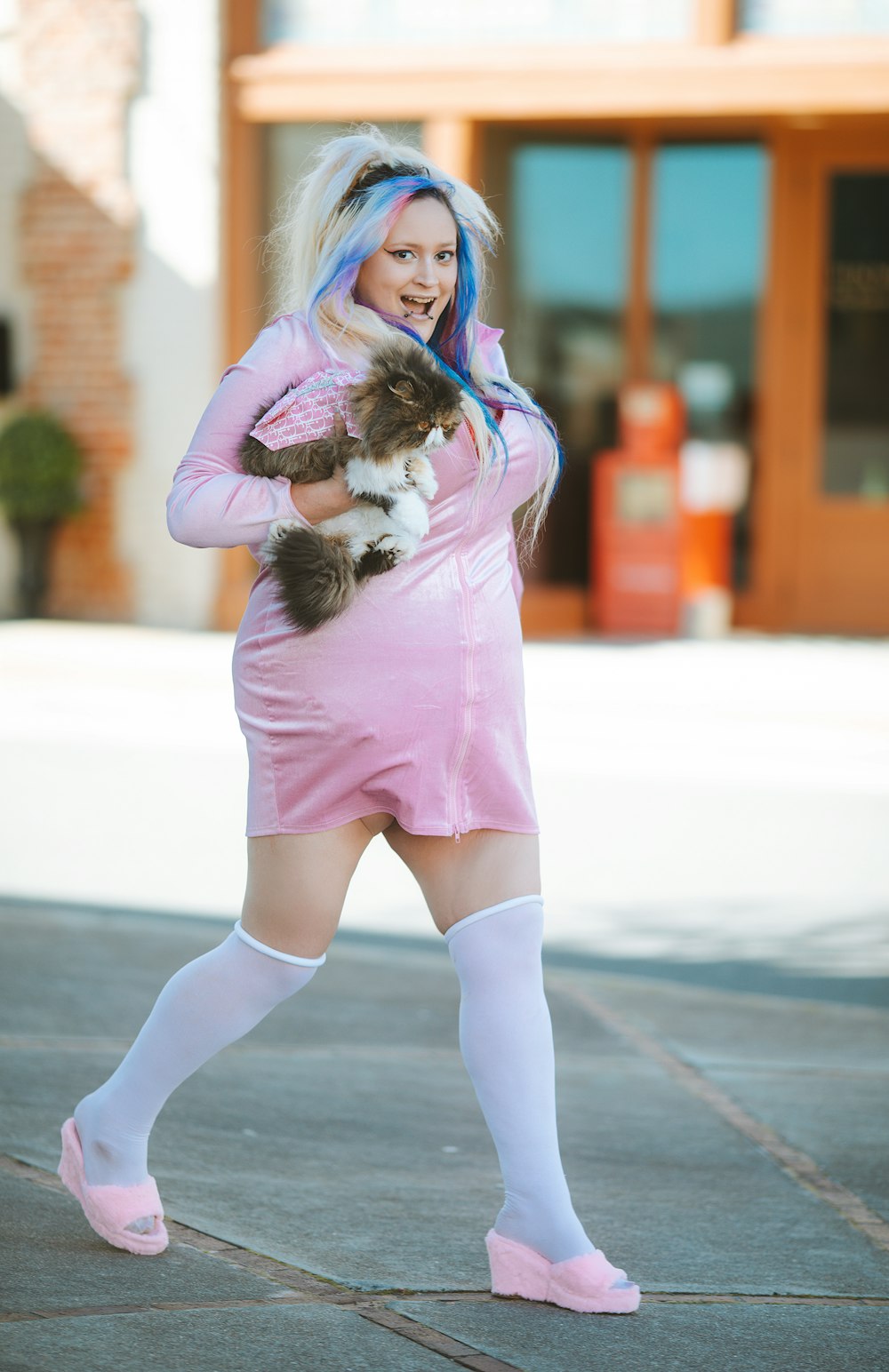 a woman in a pink dress holding a cat