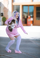 a woman in a pink dress holding a dog