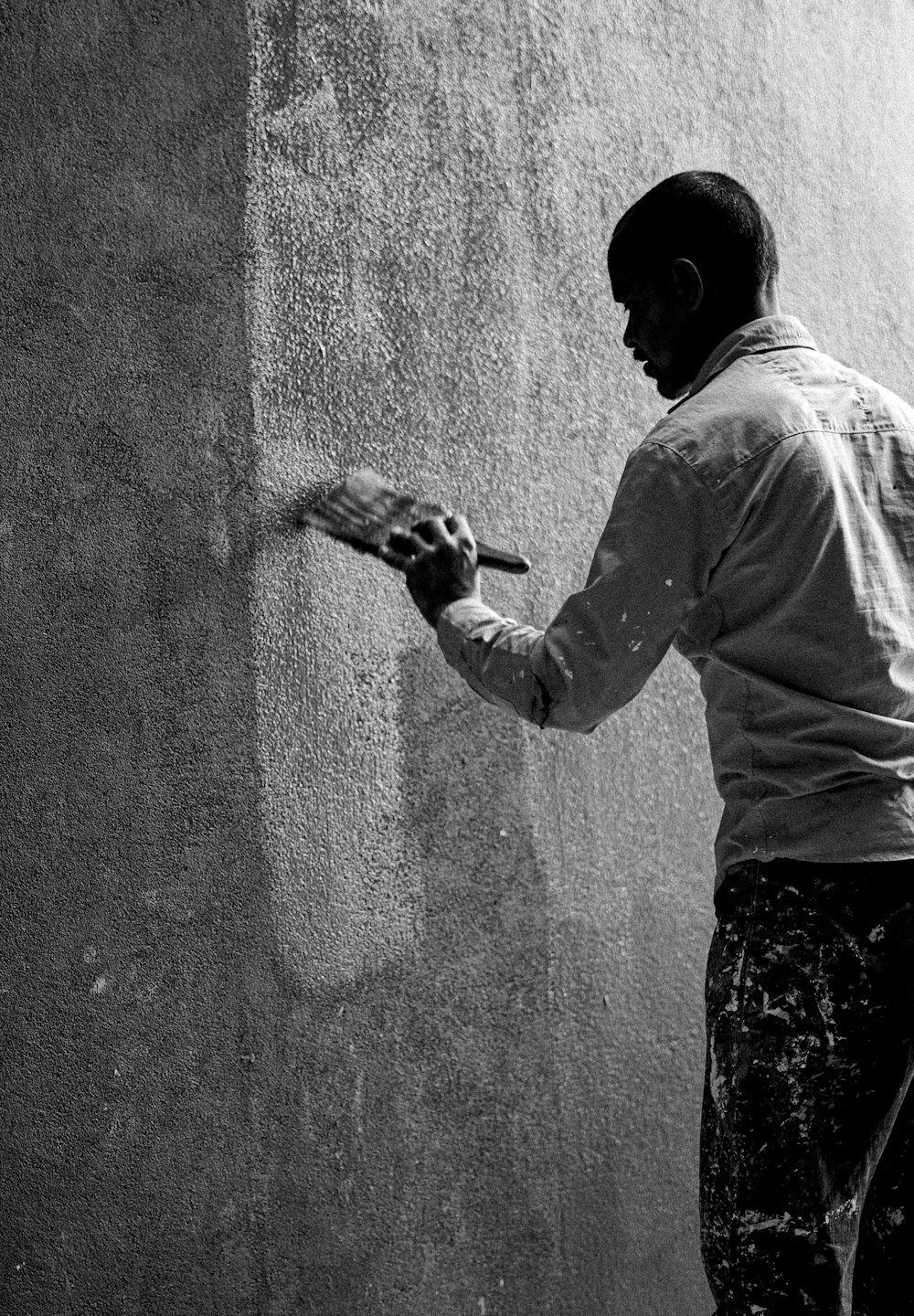 a man spray painting a wall with a spray gun
