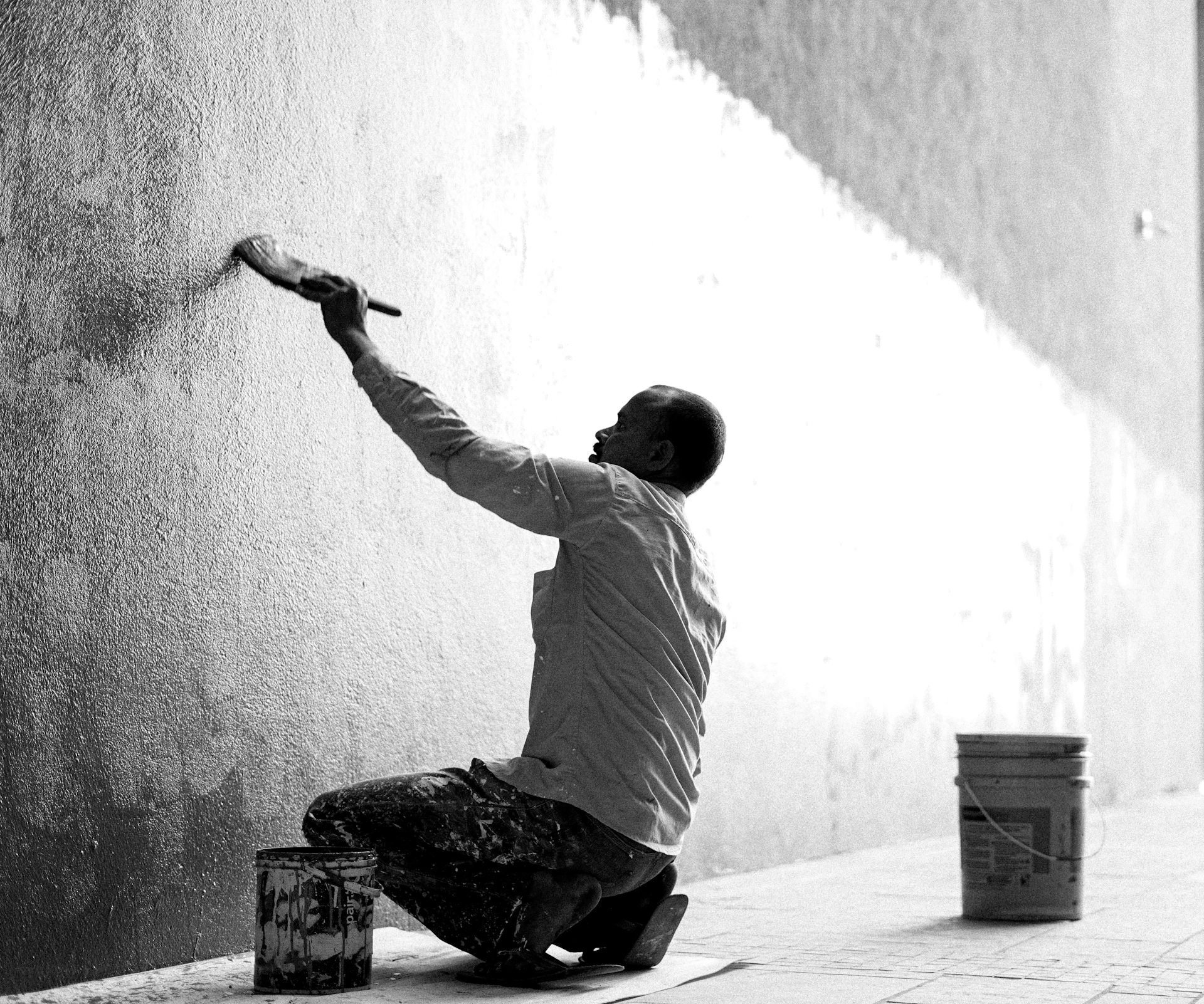 a man painting a wall with a paint roller