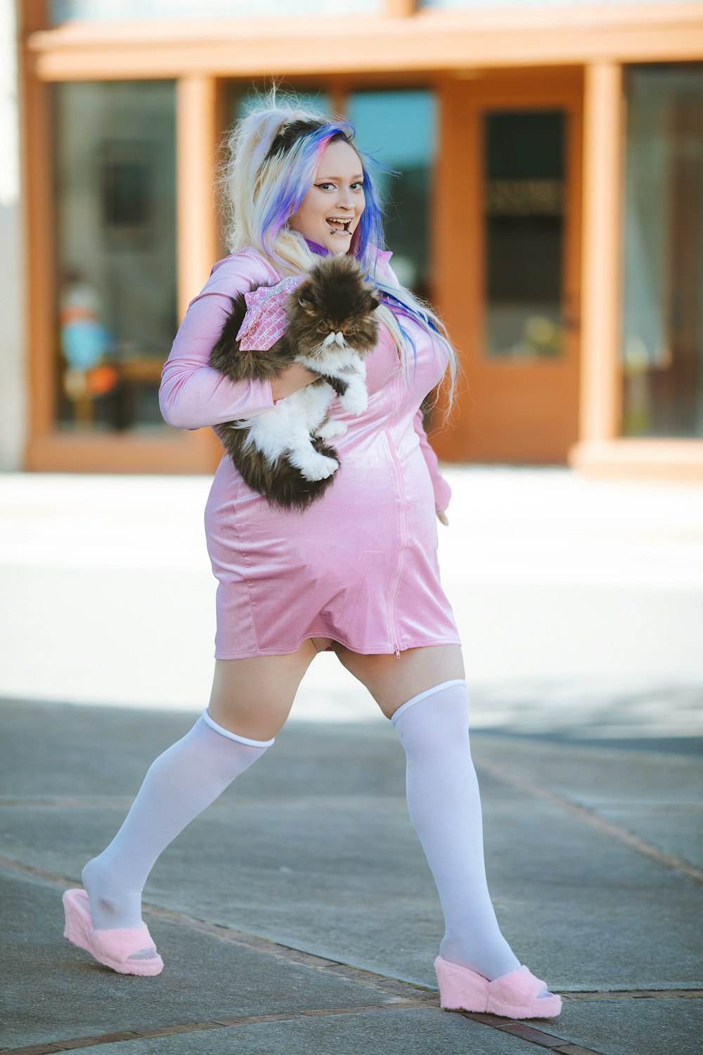Eine Frau in einem rosa Kleid, die eine Katze hält