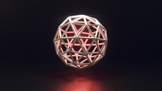 A geometric sphere composed of triangular and polygonal shapes is intricately arranged in a symmetrical pattern. The structure emits a soft pink glow from within, casting subtle reflections on a dark background.