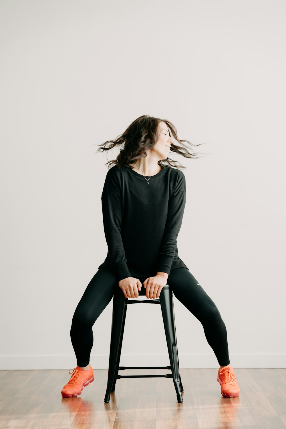 a woman sitting on a stool with her hair blowing in the wind