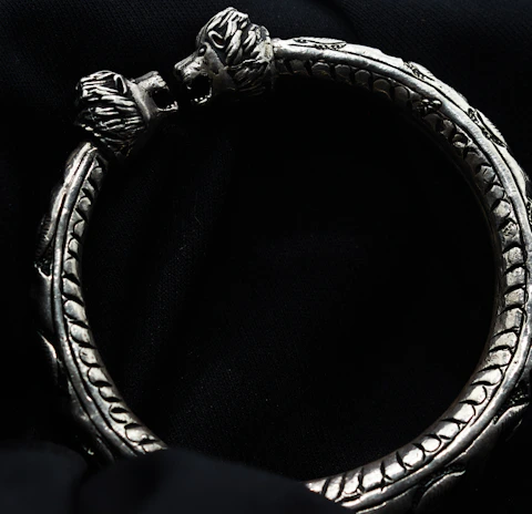 Sterling silver bracelet with intricate detailing and an 18k gold vermeil finish resting on a velvet cushion.