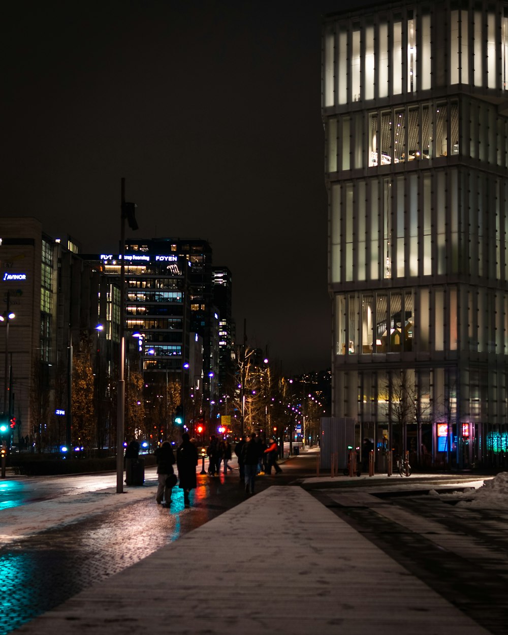 a group of people walking down a sidewalk next to a tall building