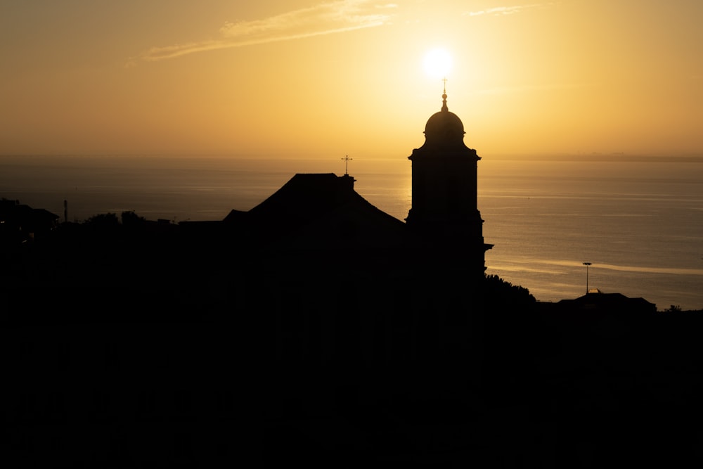 the sun is setting over a building with a steeple