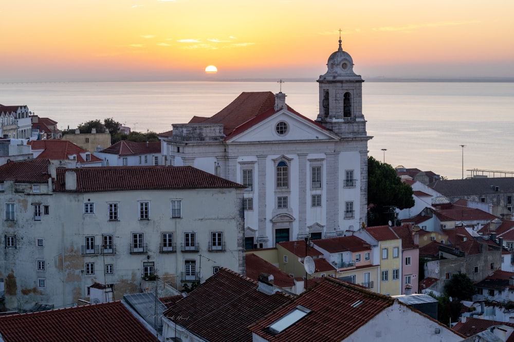 a sunset view of a city with a church and a body of water in the