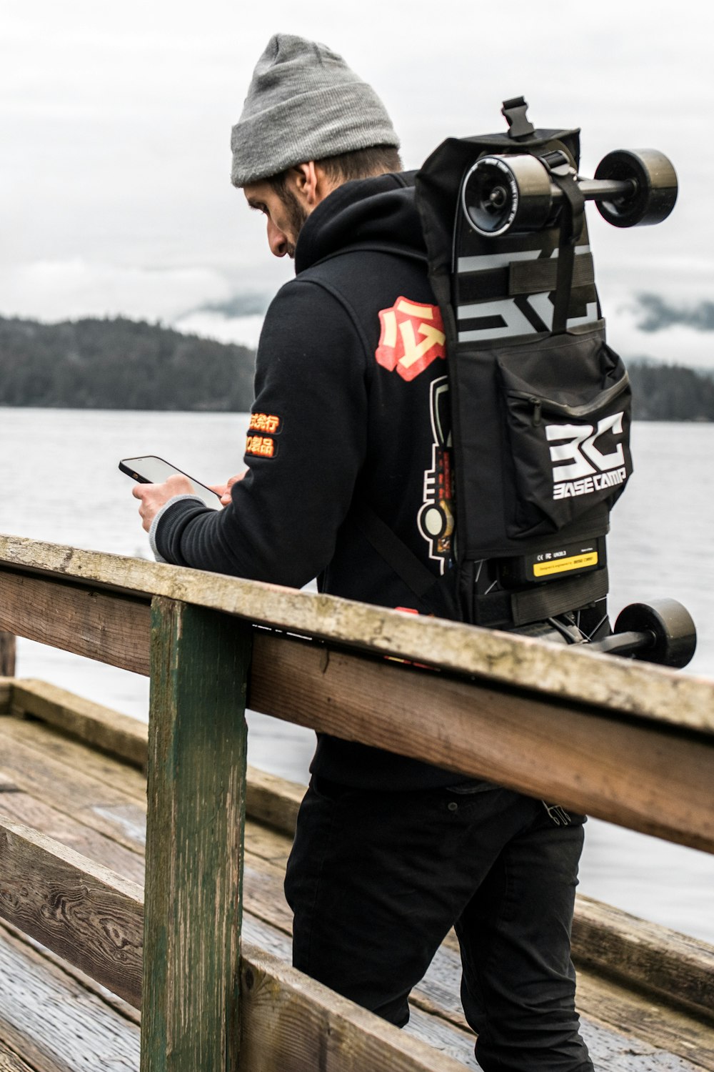 a man standing on a pier looking at his cell phone