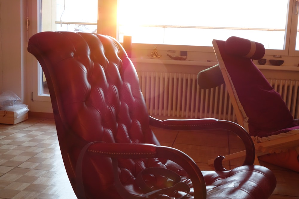 a red leather chair sitting in front of a window