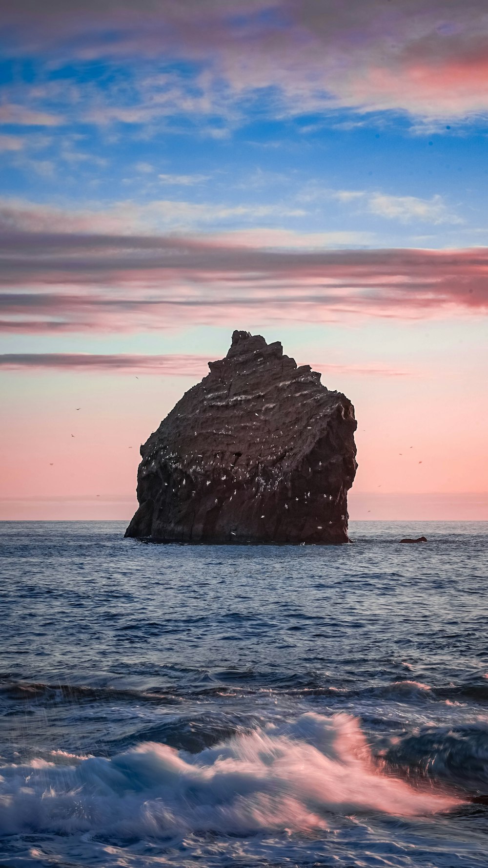 a large rock in the middle of the ocean