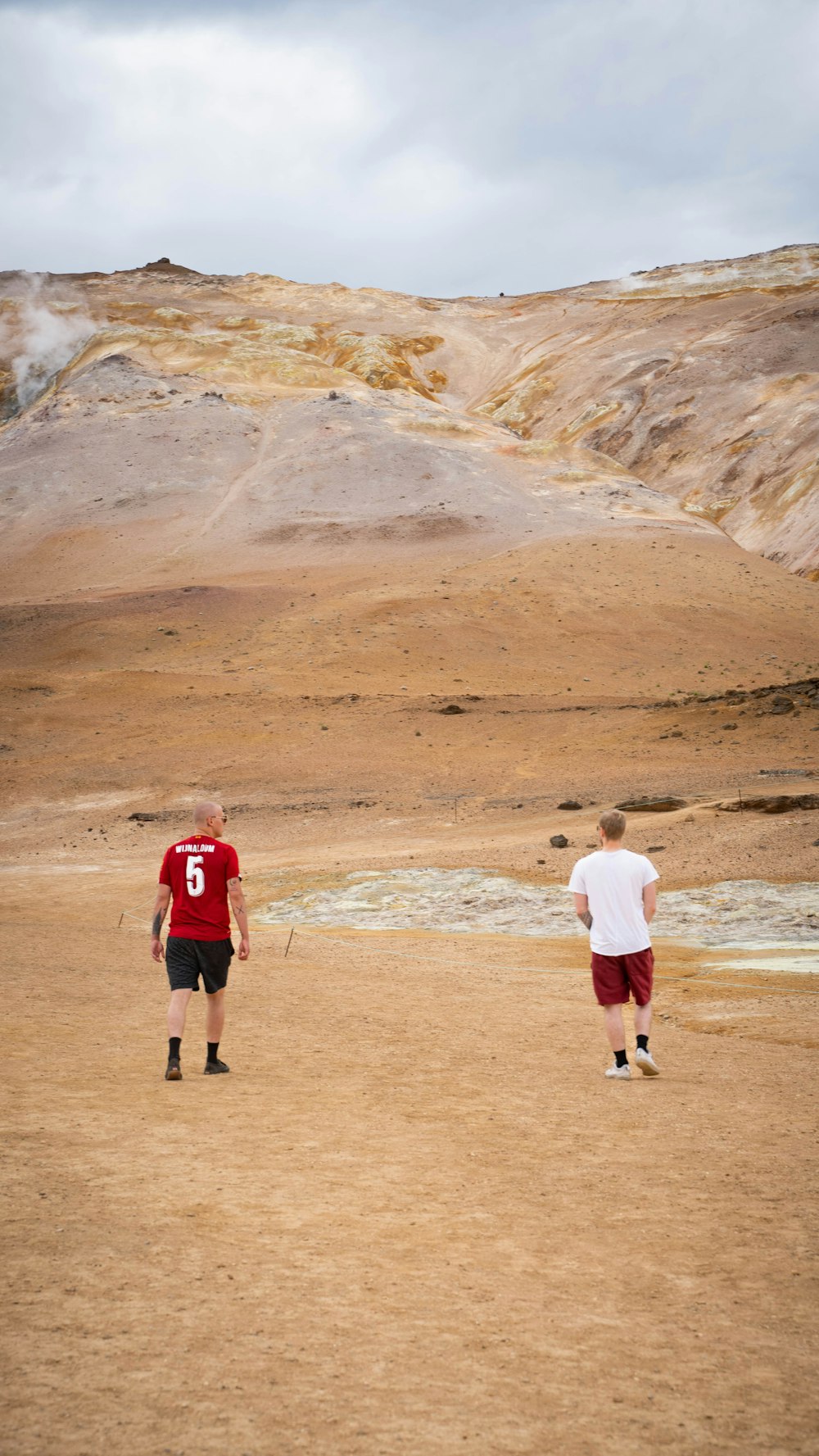 a couple of men standing on top of a dirt field