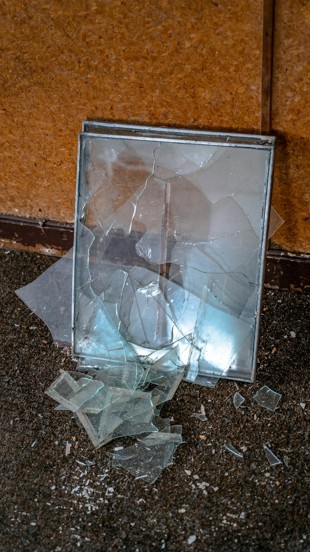 a broken mirror sitting on the ground next to a wall