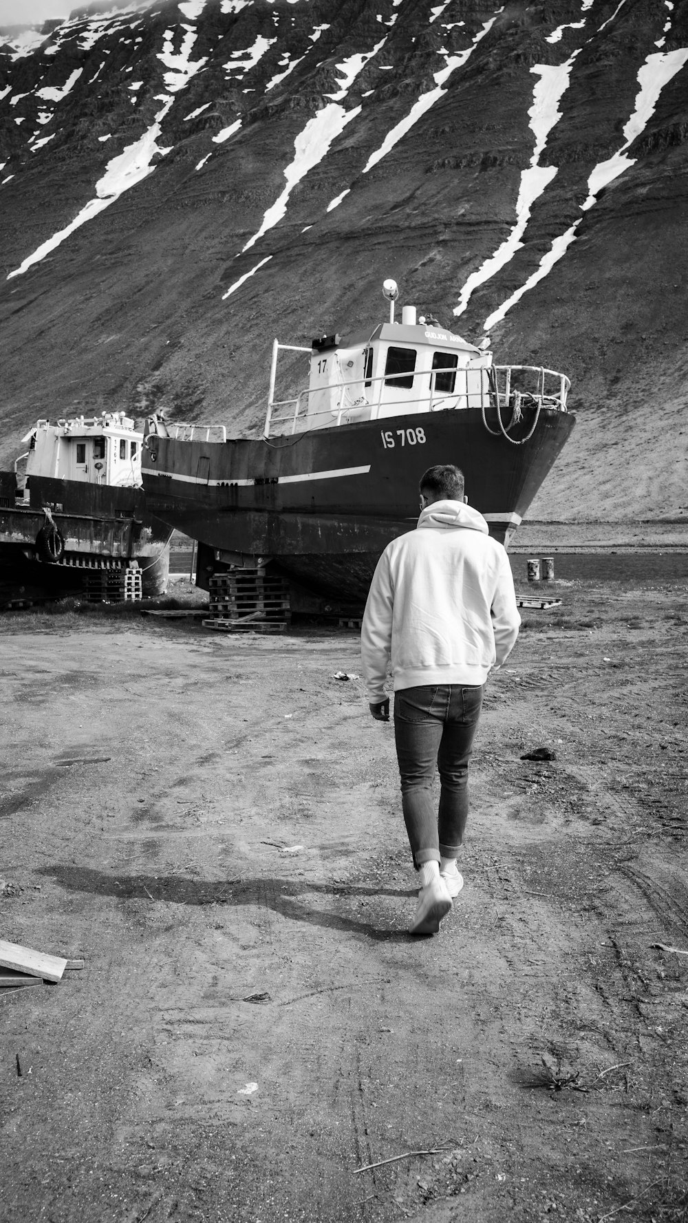 a black and white photo of a person walking towards a boat