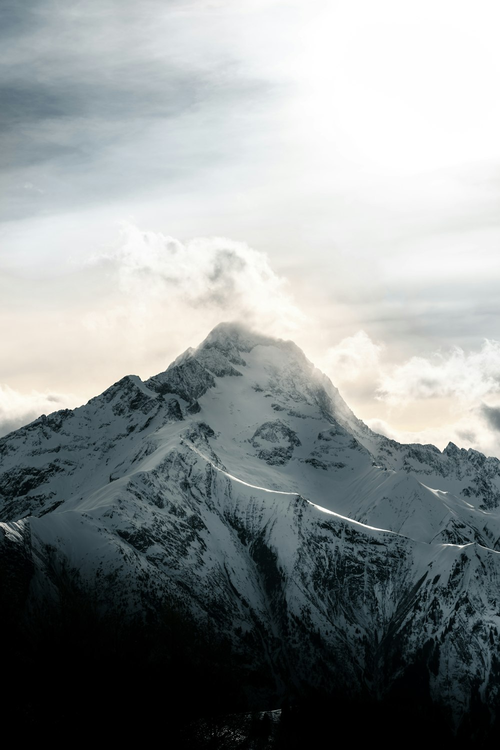 a mountain covered in snow under a cloudy sky