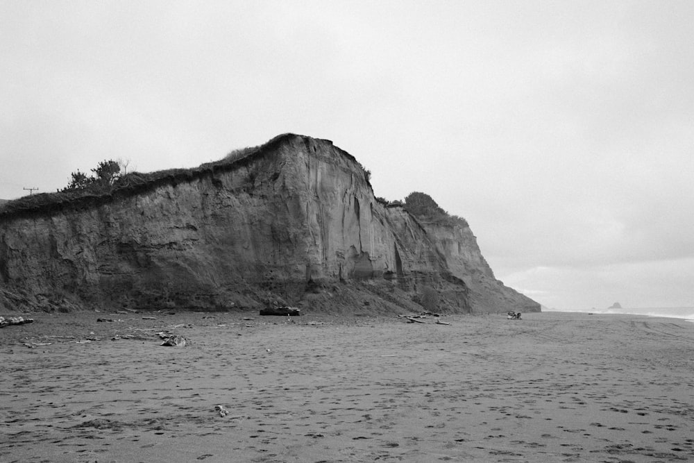 a black and white photo of a cliff on a beach