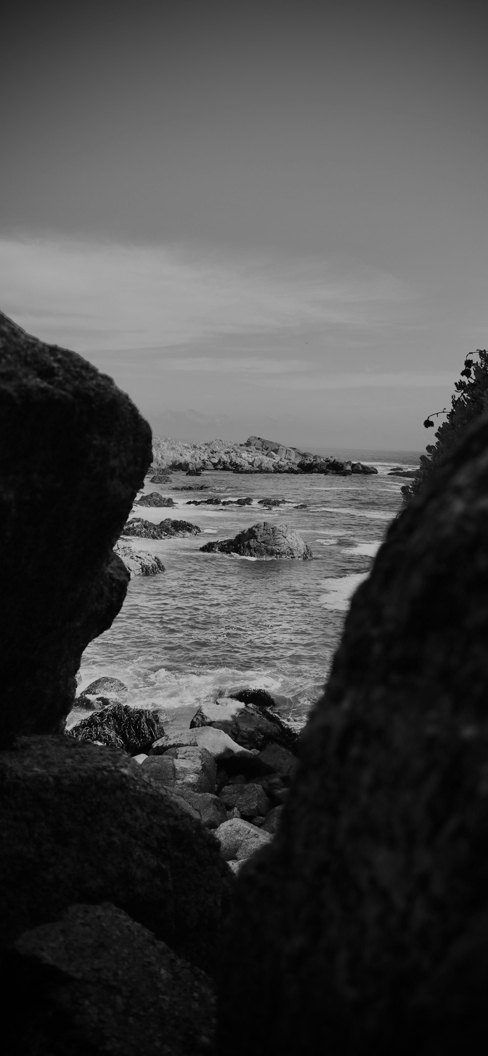 a black and white photo of the ocean and rocks