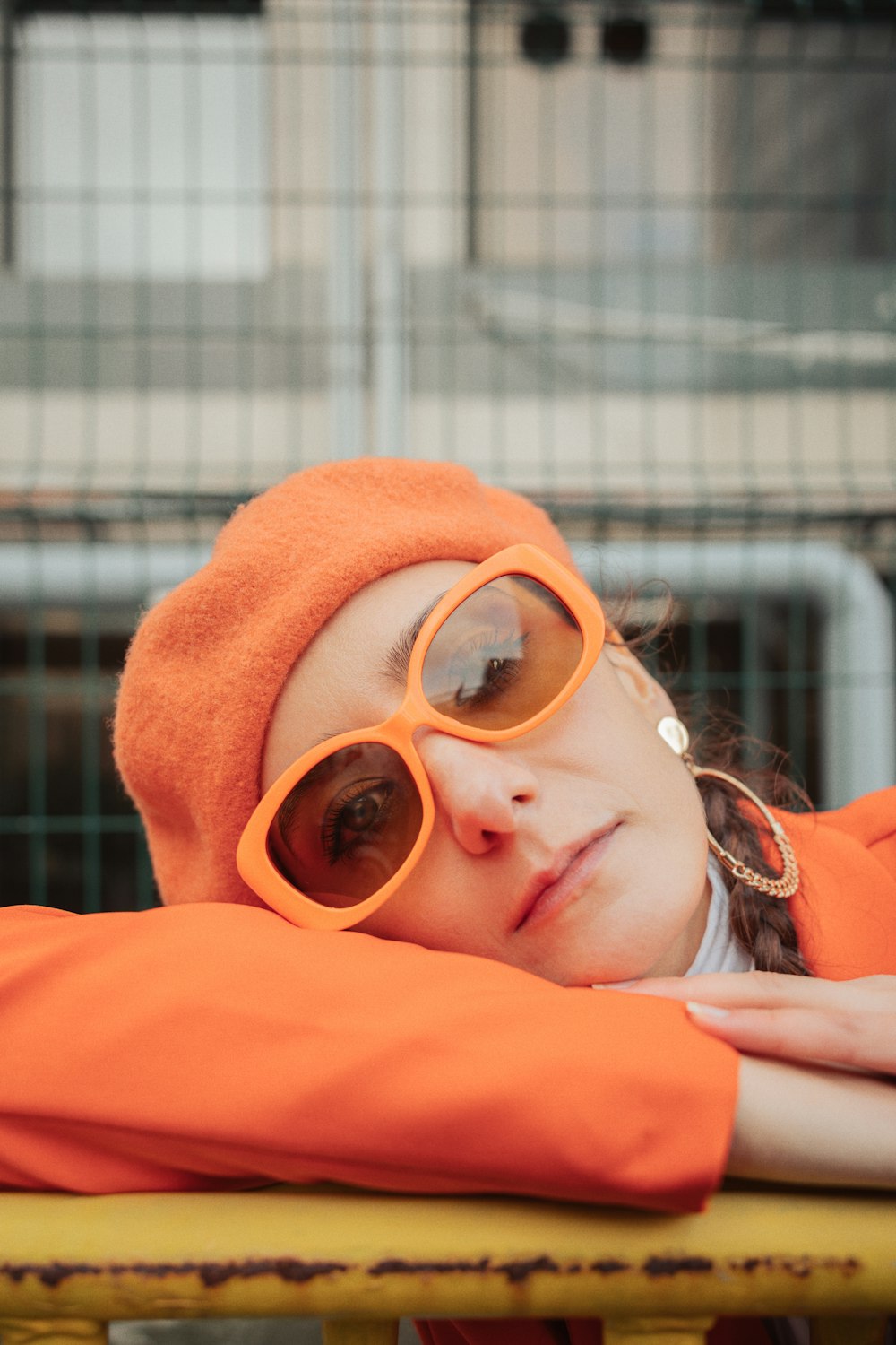 a woman wearing sunglasses and a hat laying on a bench