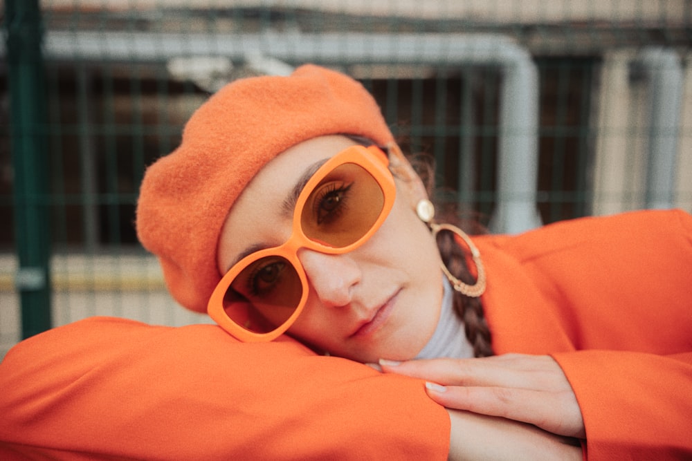 a woman wearing orange sunglasses and a hat