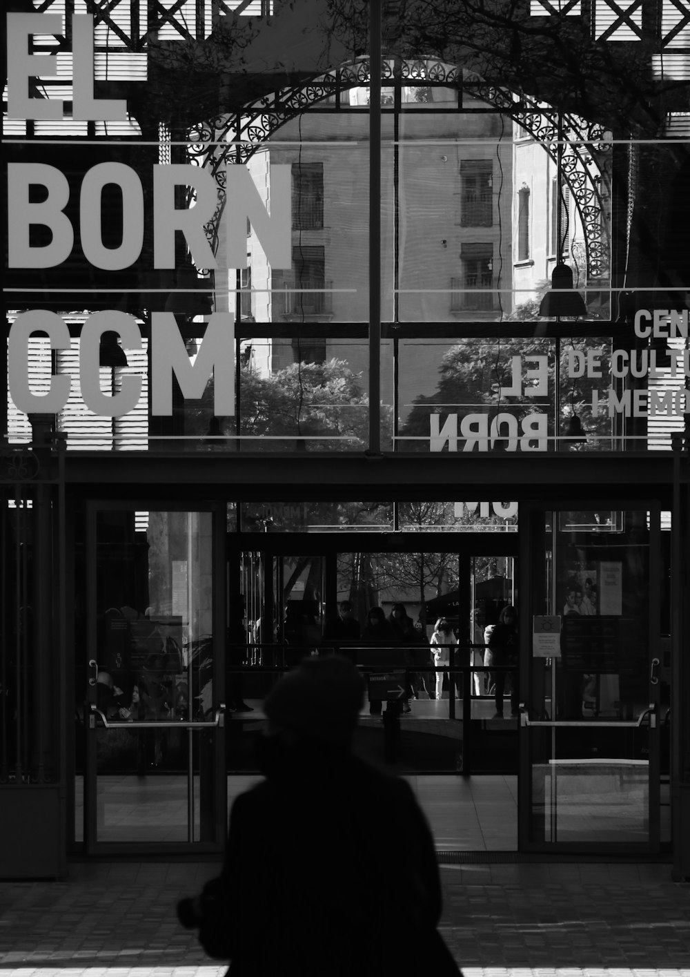 a black and white photo of a person walking in front of a building