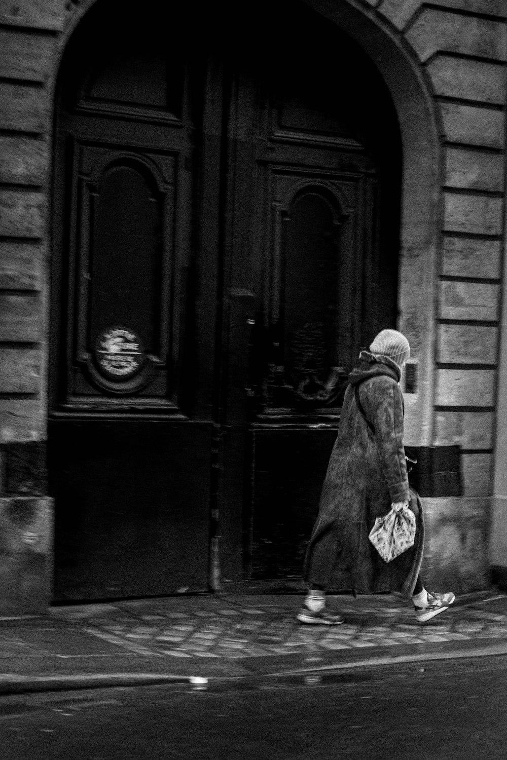 a black and white photo of a woman walking down the street