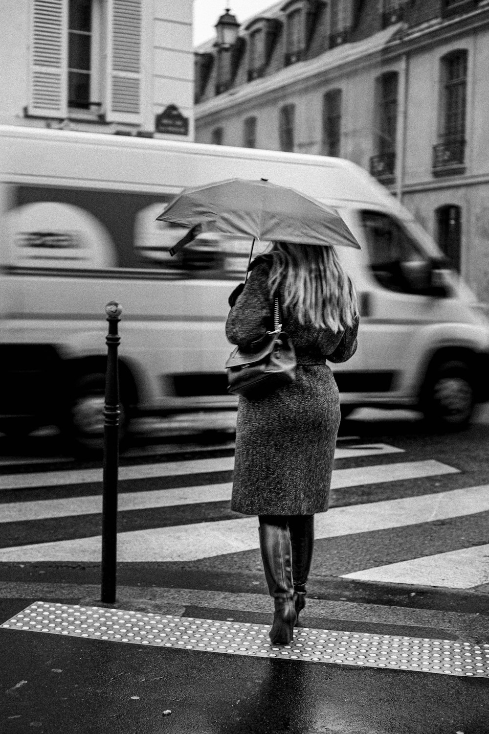 a woman walking across a street holding an umbrella