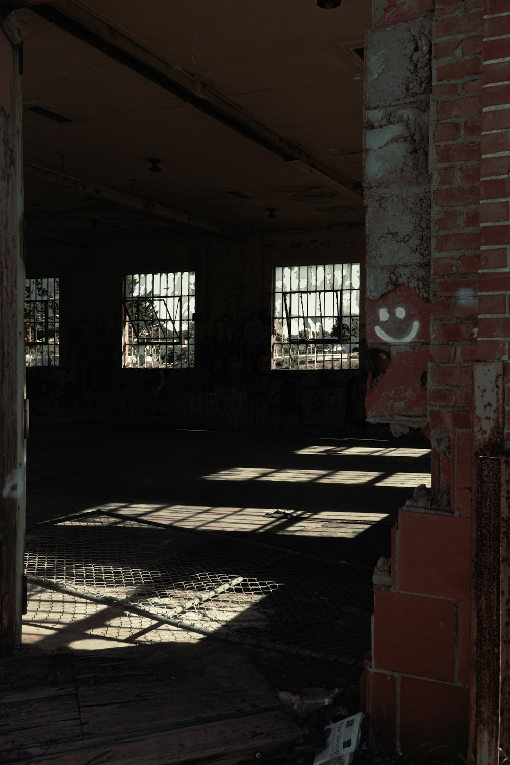an empty room with two windows and a smiley face drawn on the wall