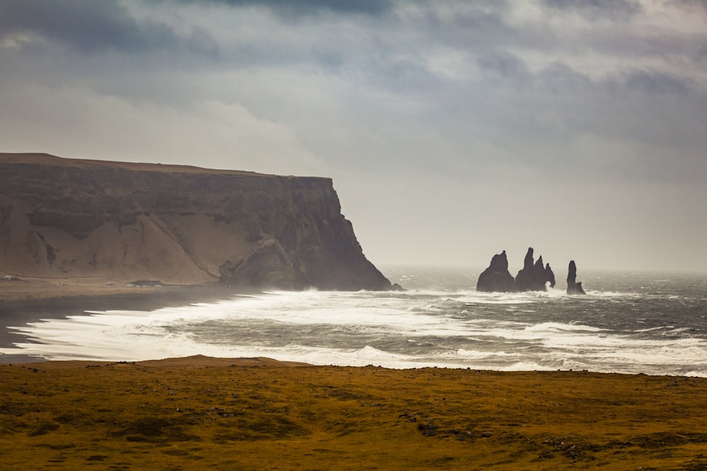 a large body of water sitting next to a rocky cliff