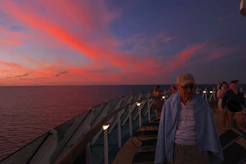 A joyful group of friends celebrating on a cruise deck with ocean views.
