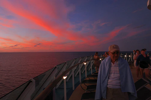 A vibrant sunset view from the deck of a cruise ship, with passengers enjoying the horizon.
