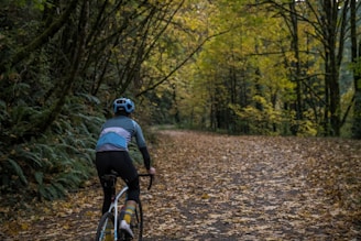 Cyclists riding through a forest path with autumn leaves