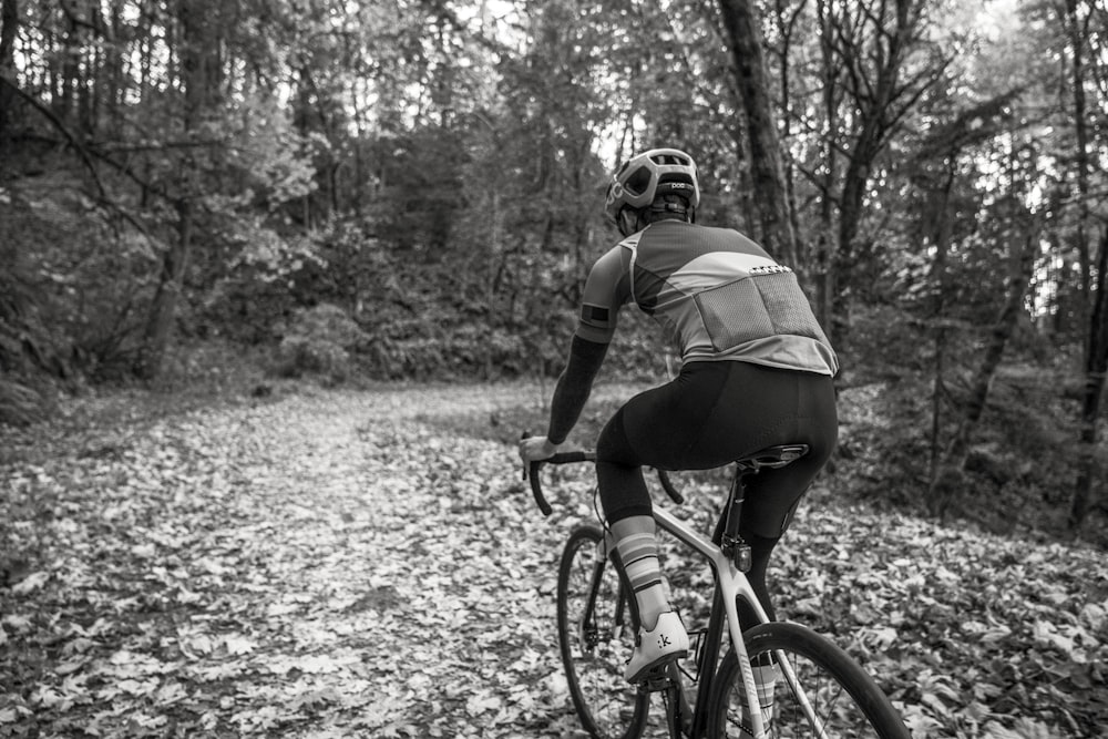 a man riding a bike down a leaf covered road