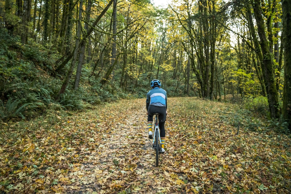 a man riding a bike down a leaf covered road
